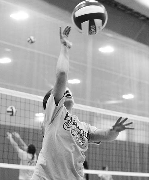 girl reaching up to spike a volleyball
